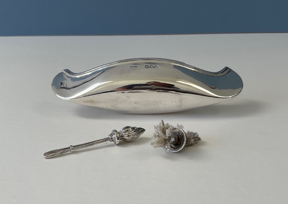 A hallmarked sterling silver table lighter shaped like a canoe with a central wick and a flame-shaped removable stopper. View III