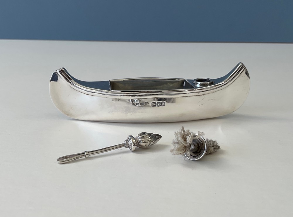 A hallmarked sterling silver table lighter shaped like a canoe with a central wick and a flame-shaped removable stopper. View IV