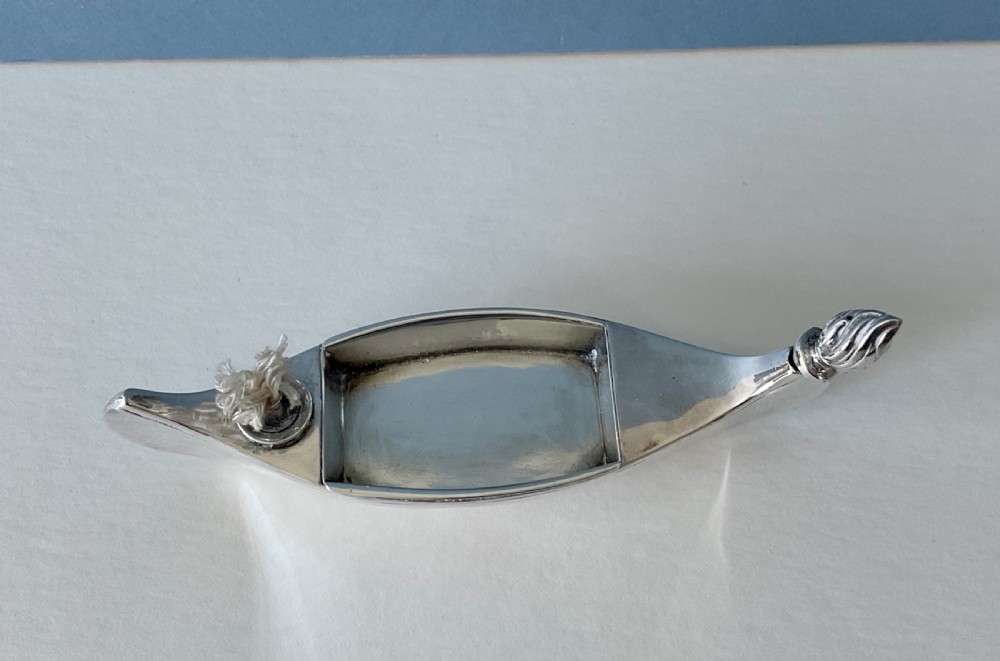 A hallmarked sterling silver table lighter shaped like a canoe with a central wick and a flame-shaped removable stopper. View VI