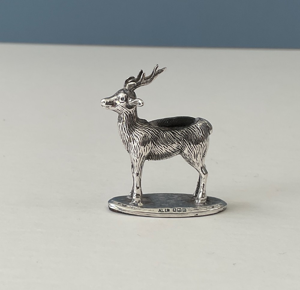 A hallmarked sterling silver pin cushion modelled in the form of a standing stag with antlers on an oval base.