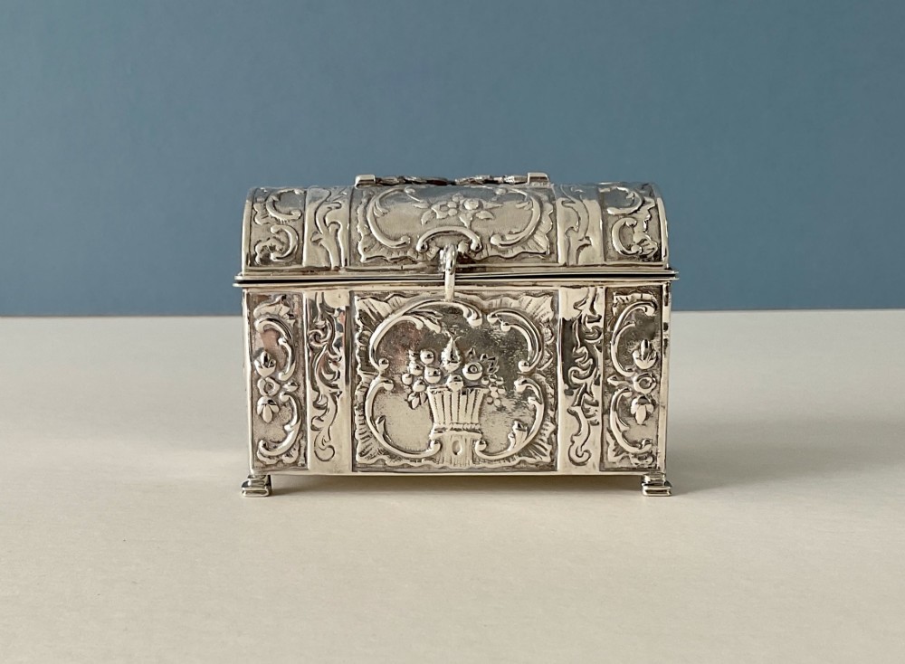 A small rectangular silver marriage casket featuring a domed lid, top handle, bracket feet, and intricate repousse scrollwork depicting birds and floral motifs. View II