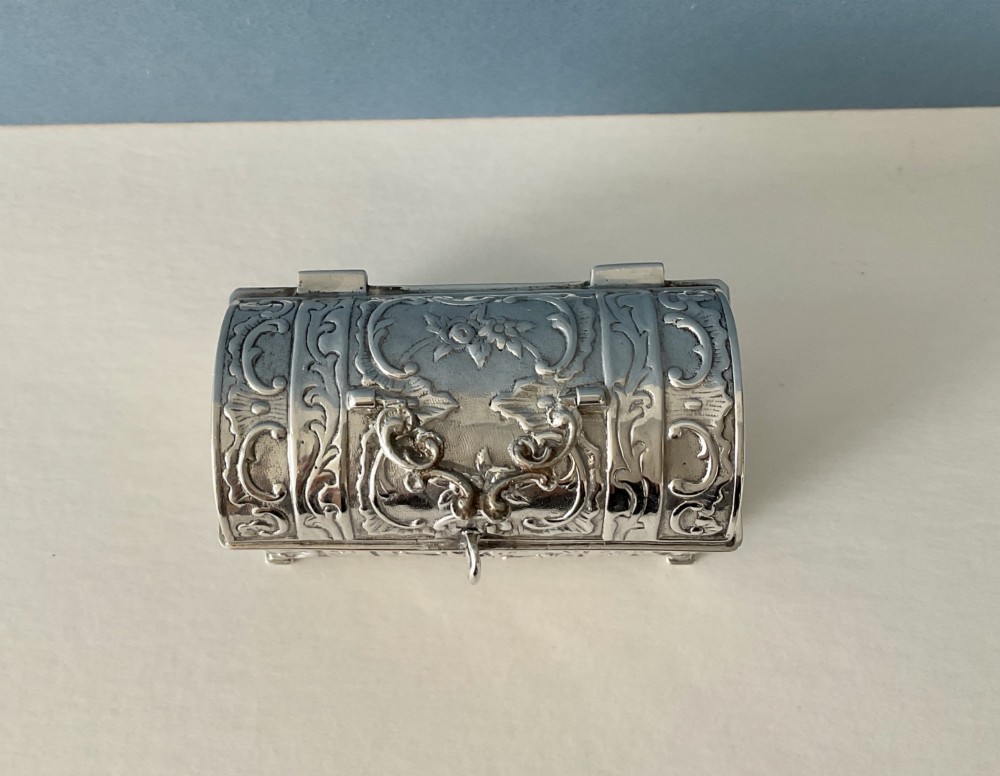 A small rectangular silver marriage casket featuring a domed lid, top handle, bracket feet, and intricate repousse scrollwork depicting birds and floral motifs. View VII