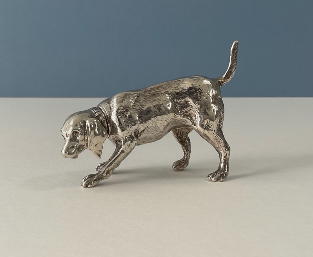 A solid silver novelty pepper pot cast in the detailed form of a standing hunting dog.