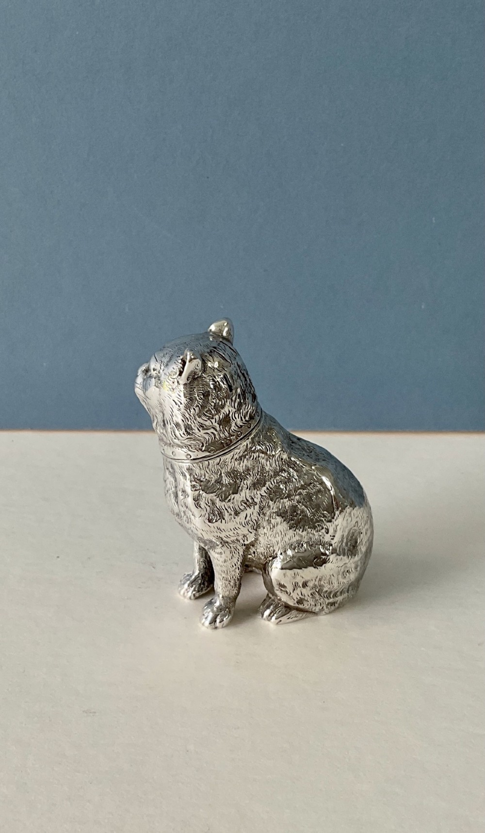 A small silver pepper caster crafted in the form of a seated cat with detailed chased fur and a collar. View III