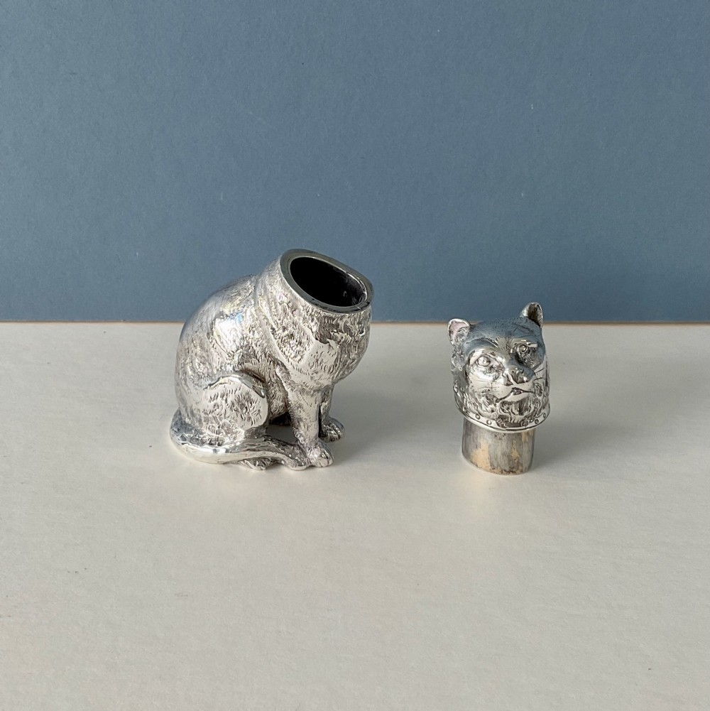 A small silver pepper caster crafted in the form of a seated cat with detailed chased fur and a collar. View V