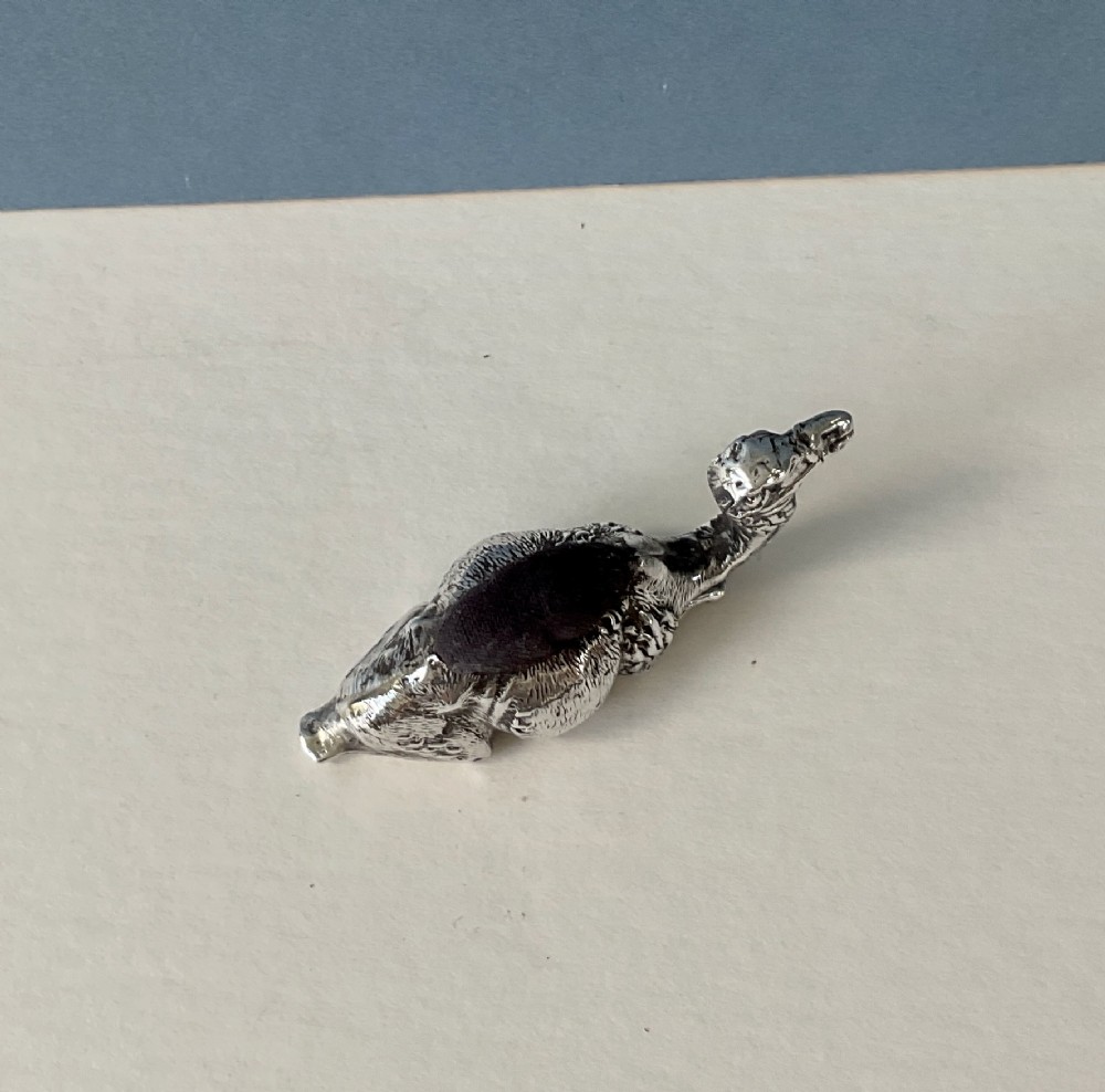 An antique silver novelty pin cushion cast in the form of a seated camel with a dark fabric cushion integrated into its back. View III