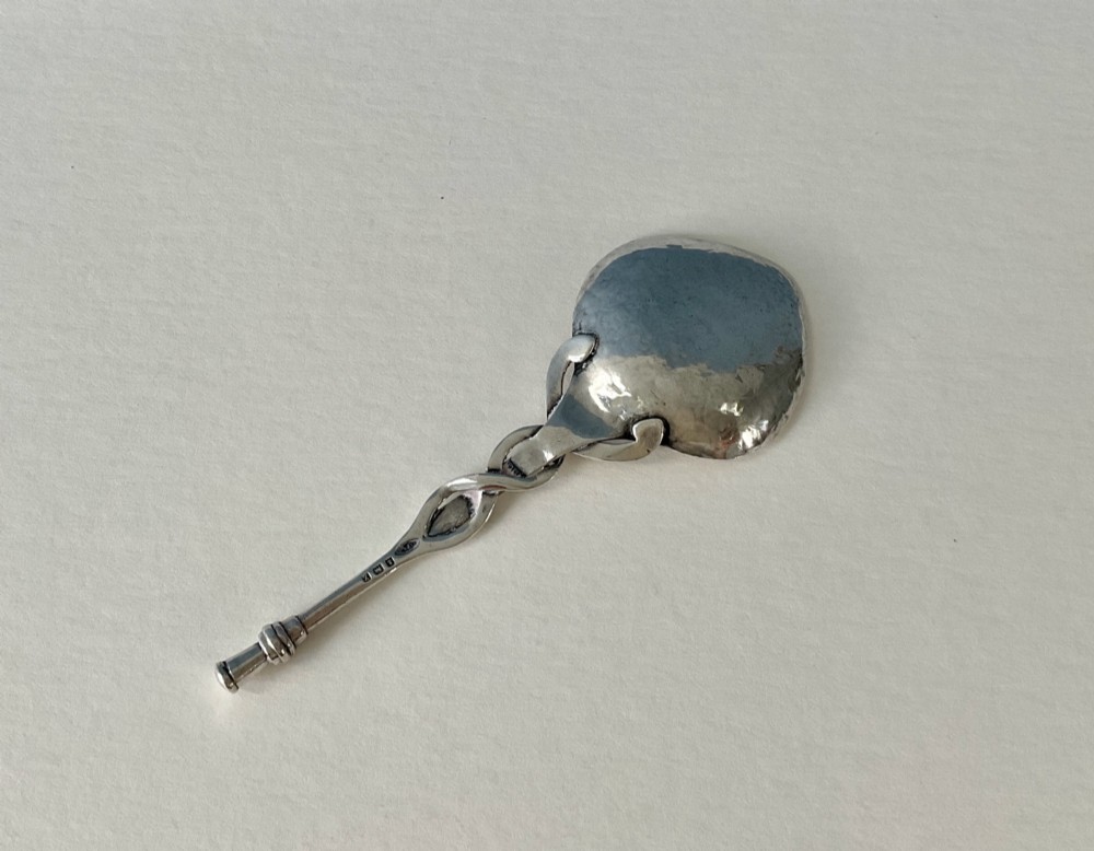 An Arts and Crafts sterling silver caddy spoon featuring a hand-hammered bowl and an intertwined stem handle. View IV