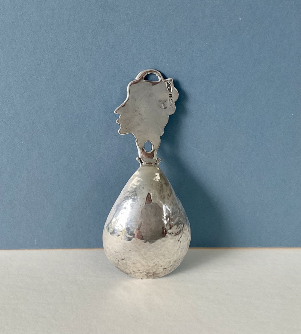A hand-hammered silver caddy spoon featuring a stylized profile head handle and a teardrop-shaped planished bowl. View II