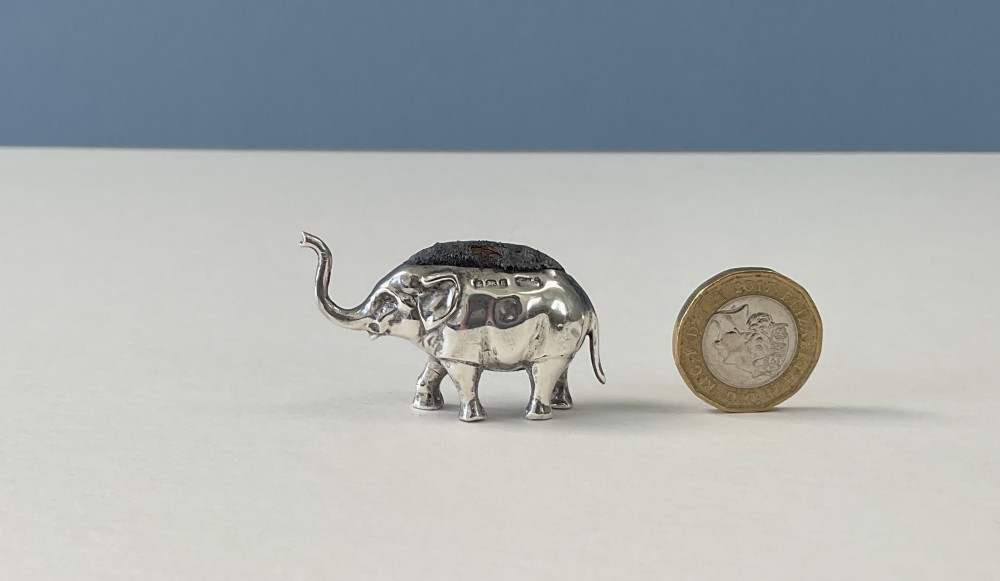 A miniature silver novelty pin cushion cast in the shape of an elephant with a dark fabric insert set into its back. View II
