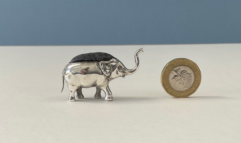 A miniature silver novelty pin cushion cast in the shape of an elephant with a dark fabric insert set into its back. View V