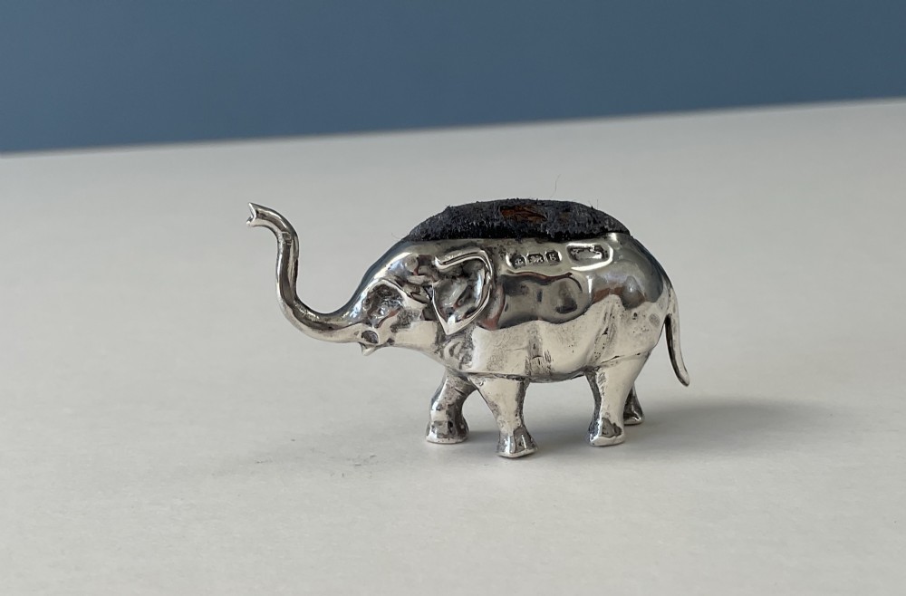 A miniature silver novelty pin cushion cast in the shape of an elephant with a dark fabric insert set into its back. View VI