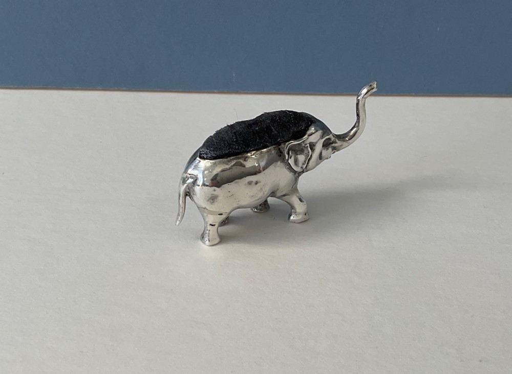 A miniature silver novelty pin cushion cast in the shape of an elephant with a dark fabric insert set into its back. View VII