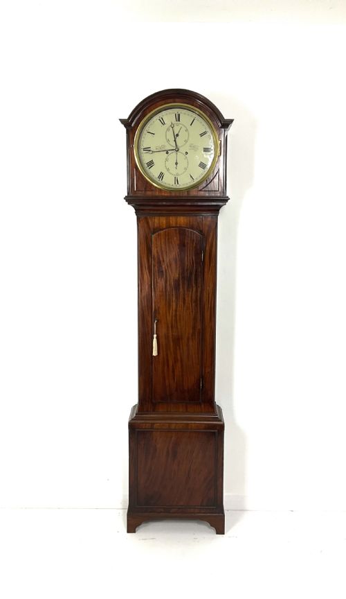 fig 2. A Regency period flame mahogany longcase clock featuring a circular brass bezel, Roman numerals, subsidiary seconds display, and an arched bonnet.