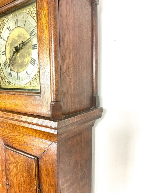 fig 1. An antique Georgian oak longcase clock hood with a square brass dial, engraved numerals, corner spandrels, and turned side columns.