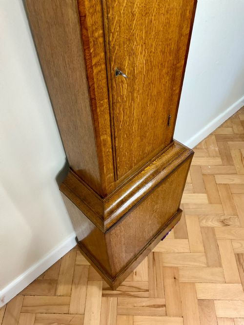 fig 1. An antique Georgian longcase clock hood crafted from light oak with an arched glass door, brass-capped side columns, and a painted white dial with Roman numerals.