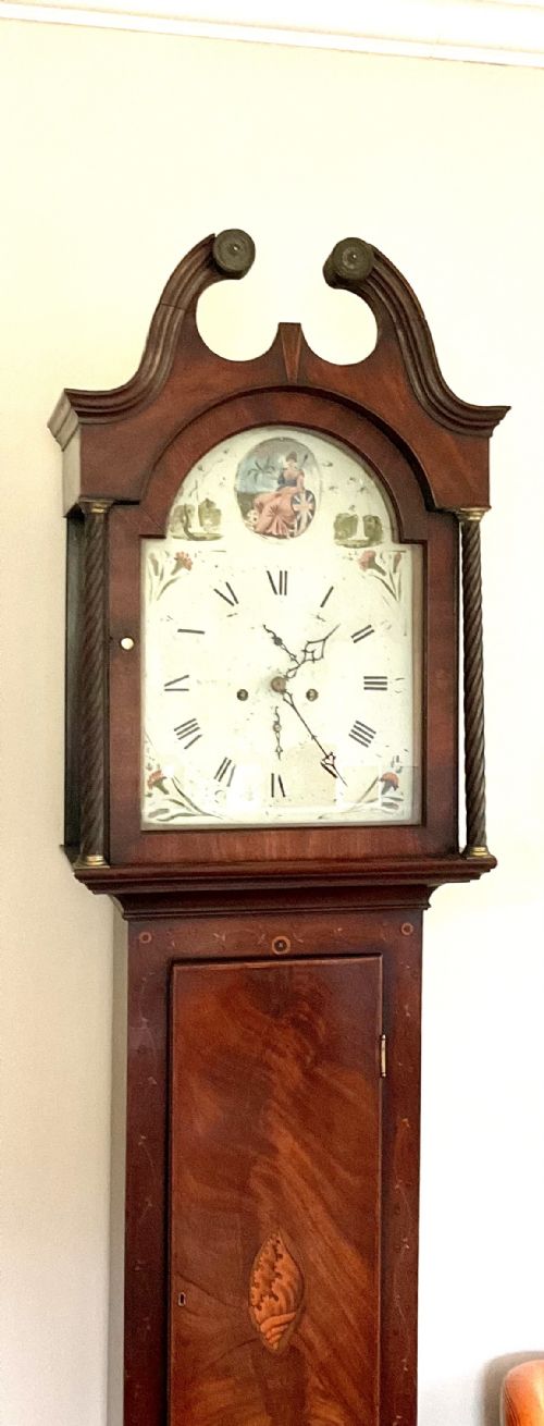 fig 1. A Georgian mahogany longcase clock featuring a swan-neck pediment, painted dial, shell marquetry inlay, and reeded side columns.
