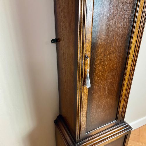 fig 1. An antique dark oak longcase grandfather clock featuring an arched hood, brass dial with silvered chapter ring, and a tall panelled trunk.
