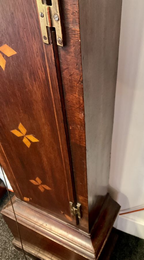 fig 2. A Georgian mahogany longcase clock featuring geometric wood inlay, a brass dial with a silvered chapter ring, and turned columns flanking the hood.