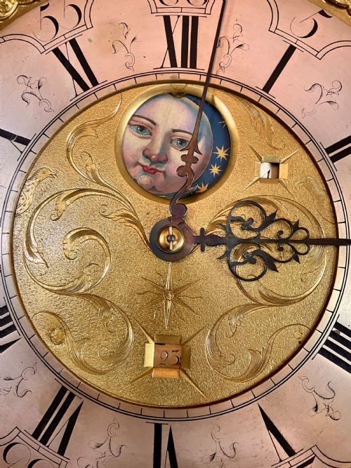 fig 1. A close-up detail of an antique brass clock dial featuring a hand-painted penny moon face set against a blue sky with gold stars.