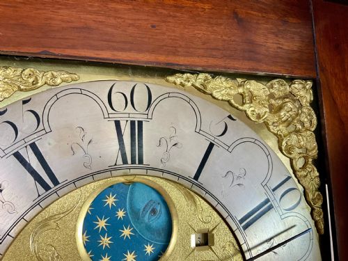 fig 2. A close-up detail of an antique brass clock dial featuring a hand-painted penny moon face set against a blue sky with gold stars.