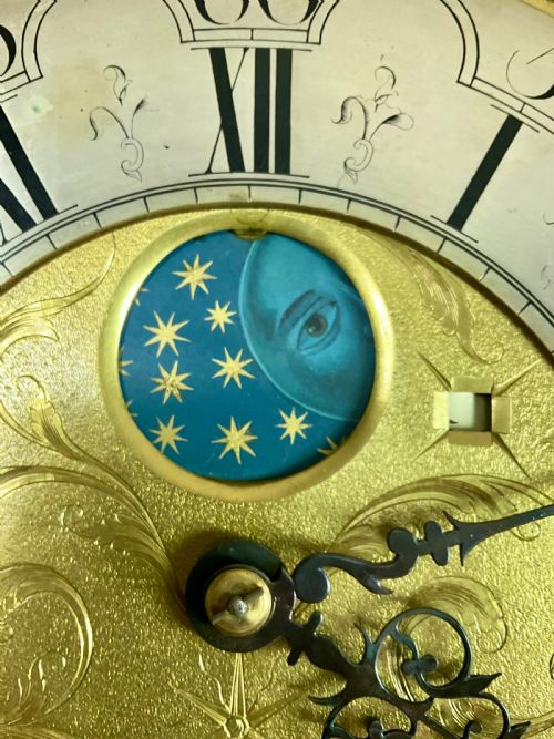 fig 3. A close-up detail of an antique brass clock dial featuring a hand-painted penny moon face set against a blue sky with gold stars.
