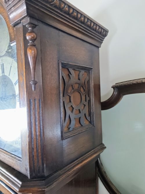 fig 1. A dark oak longcase clock featuring an arched hood, a brass dial with silvered chapter ring, and an astragal glazed trunk door.