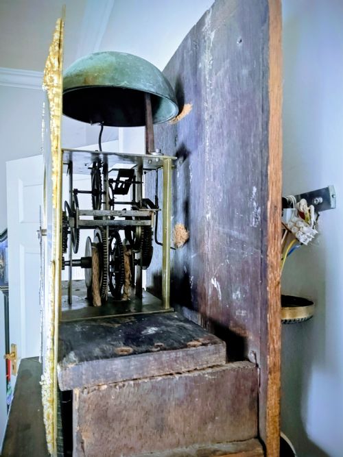 fig 1. An antique Queen Anne ebonised longcase clock featuring a square brass dial with Roman numerals and ornate corner spandrels.
