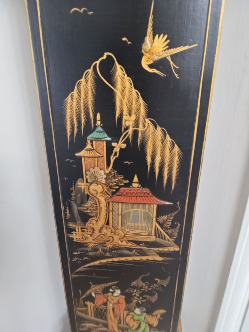 fig 1. A slender black lacquer grandmother clock decorated with gilded chinoiserie landscape motifs and fitted with an arched brass dial.