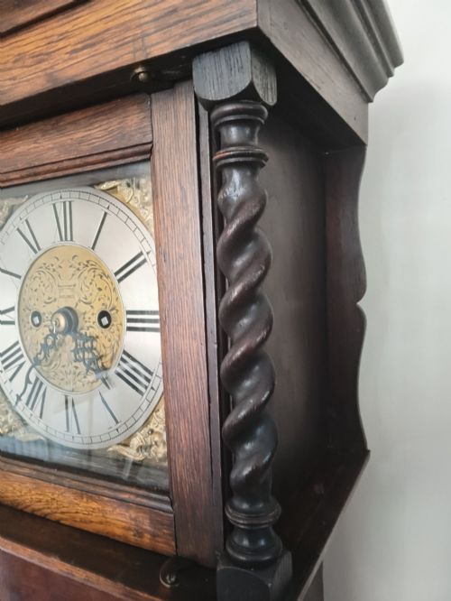fig 1. A 19th-century dark oak grandmother clock featuring barley twist side pillars, a square glass hood, and a brass dial with Roman numerals.