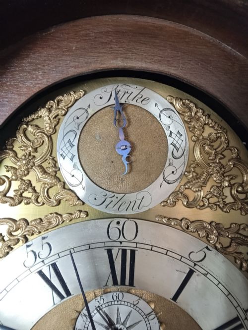 fig 1. An antique Georgian longcase clock in dark mahogany featuring an arched hood and a brass dial with a strike-silent selector.