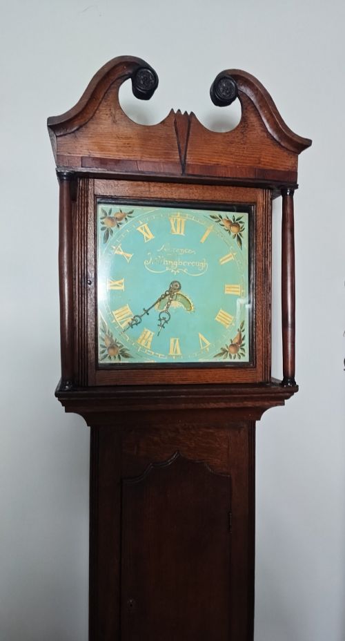 fig 2. A Georgian oak longcase clock featuring a swan-neck pediment, arched trunk door, and a painted duck egg blue square dial with Roman numerals.