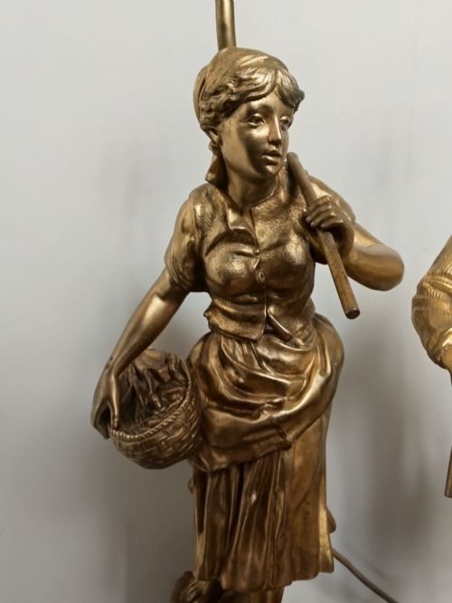 fig 1. A pair of gold gilt metal table lamps depicting standing figures of French rustic workers mounted on square wooden bases.