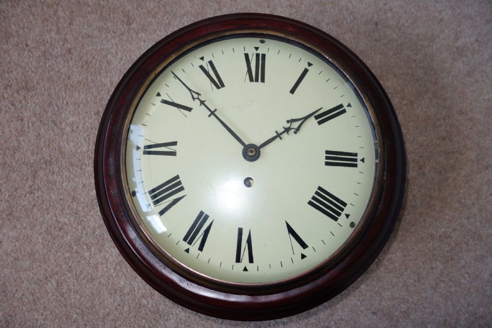 A circular antique mahogany wall clock with a convex glass face, brass bezel, and cream dial displaying black Roman numerals.