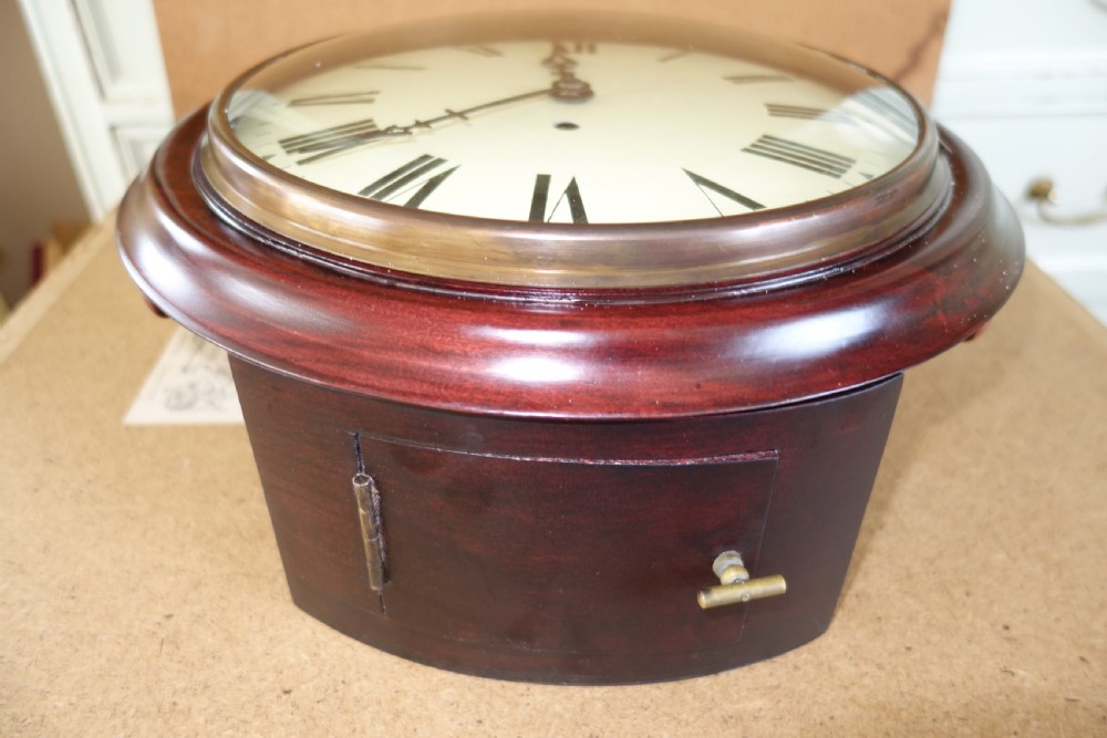 A circular antique mahogany wall clock with a convex glass face, brass bezel, and cream dial displaying black Roman numerals. View IV