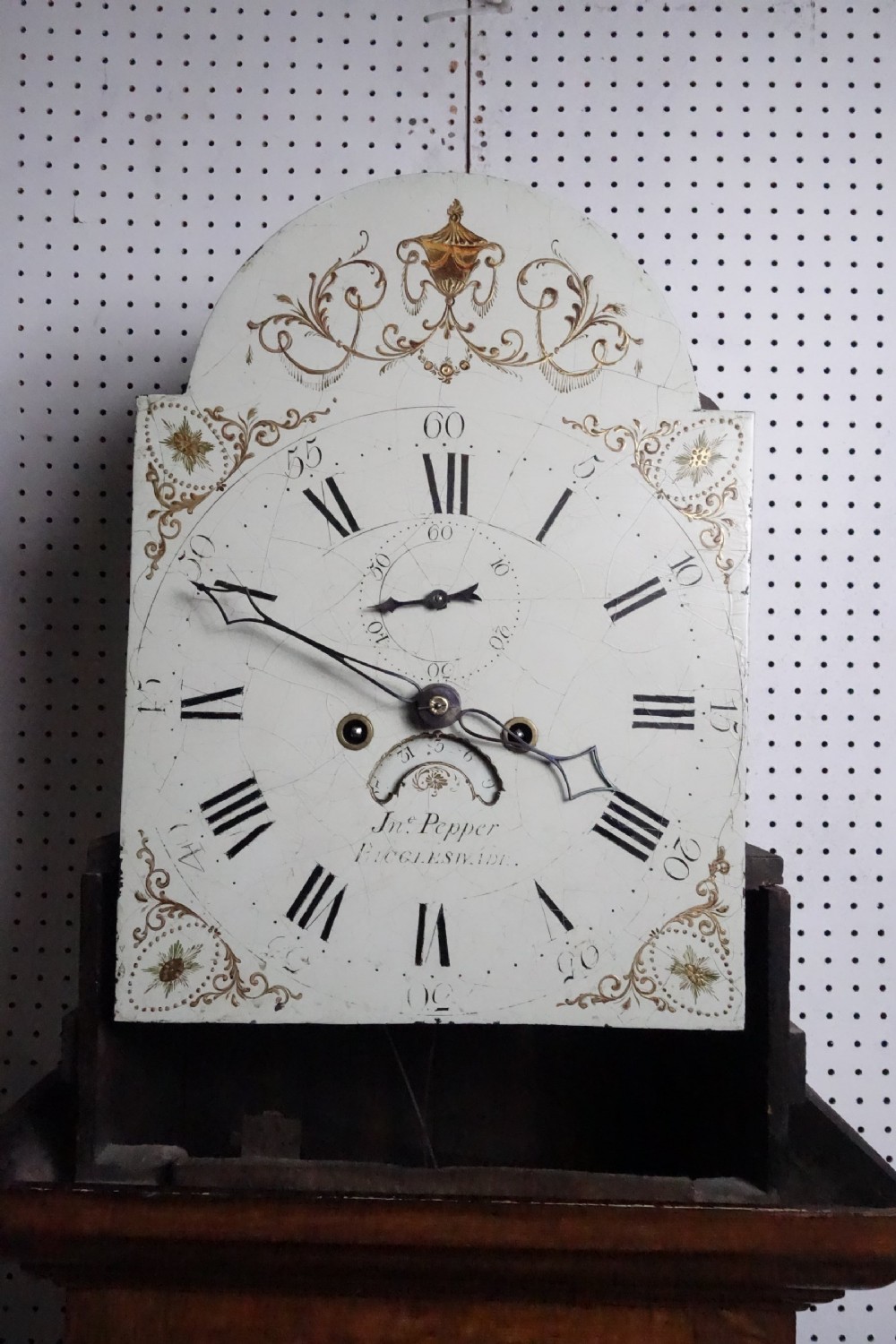 Georgian light oak longcase clock hood with brass finials, arched glass door, and white painted dial featuring Roman numerals. View III