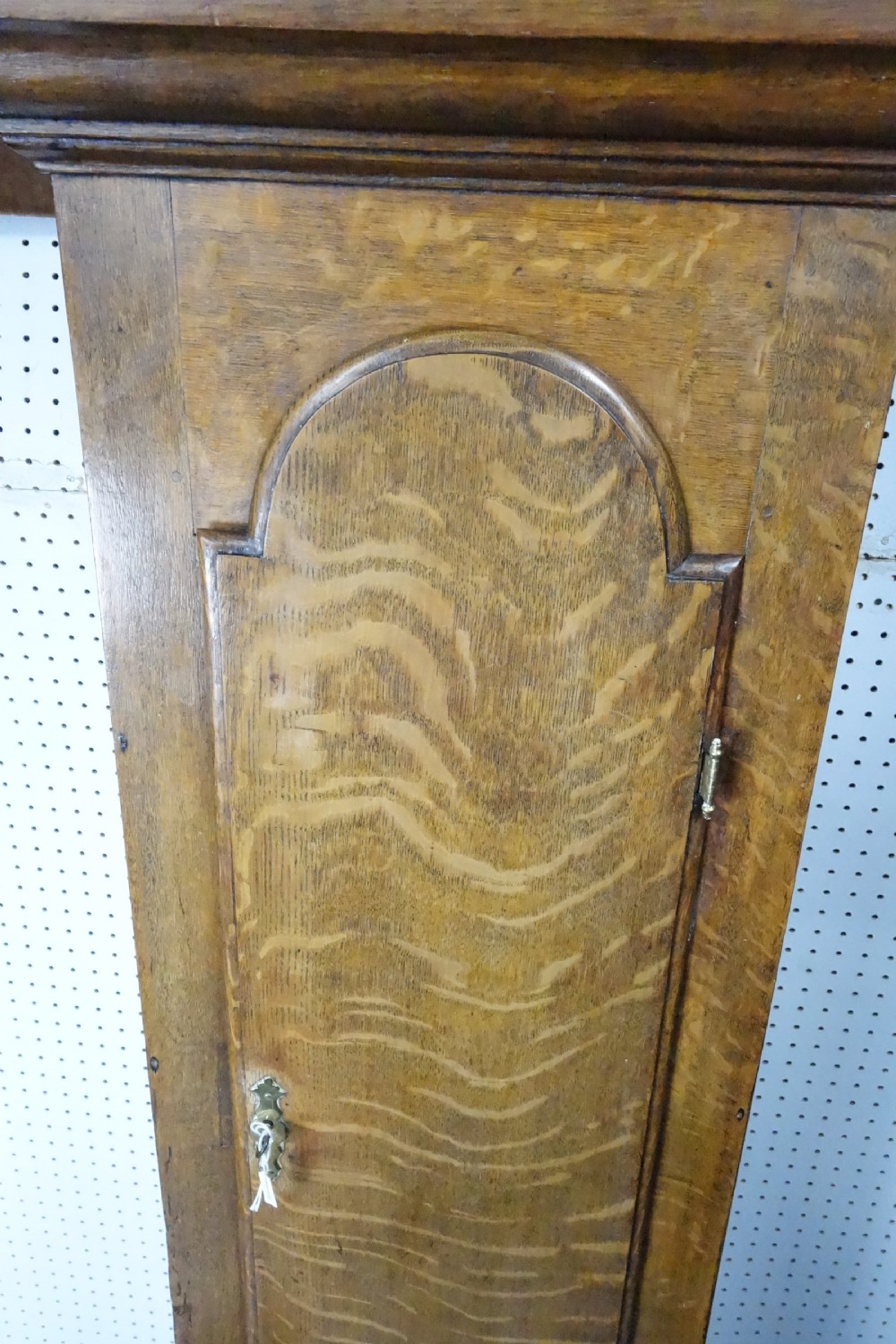 Georgian light oak longcase clock hood with brass finials, arched glass door, and white painted dial featuring Roman numerals. View VI