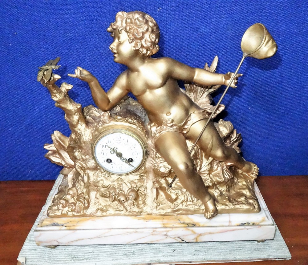 A nineteenth-century French gilt metal mantel clock featuring a sculpted cherub reaching for a dragonfly, mounted atop a variegated marble base.