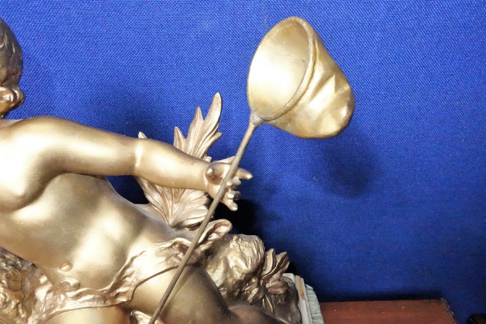 A nineteenth-century French gilt metal mantel clock featuring a sculpted cherub reaching for a dragonfly, mounted atop a variegated marble base. View III