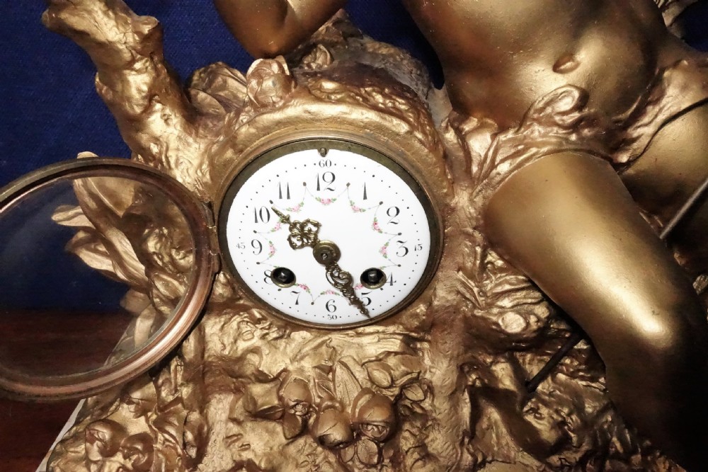 A nineteenth-century French gilt metal mantel clock featuring a sculpted cherub reaching for a dragonfly, mounted atop a variegated marble base. View IV