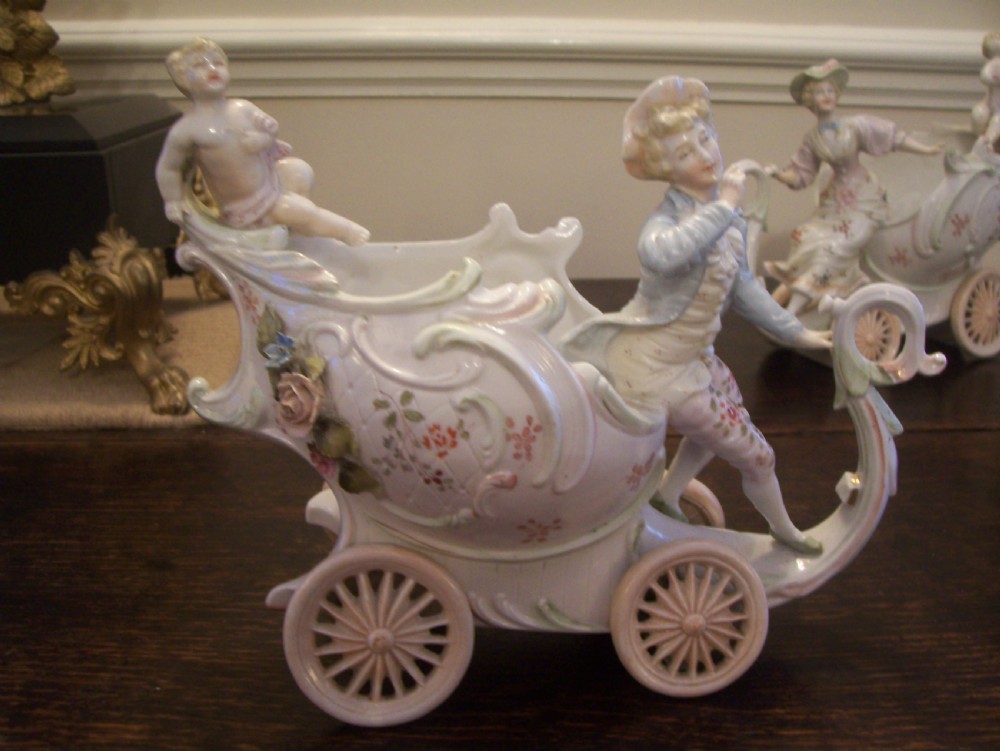 A pair of 19th-century pastel porcelain chariot vases featuring sculpted male and female figures with cherubs and scroll details. View II