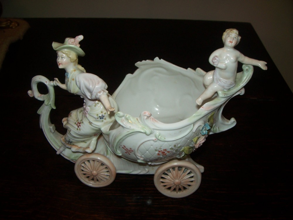 A pair of 19th-century pastel porcelain chariot vases featuring sculpted male and female figures with cherubs and scroll details. View IV