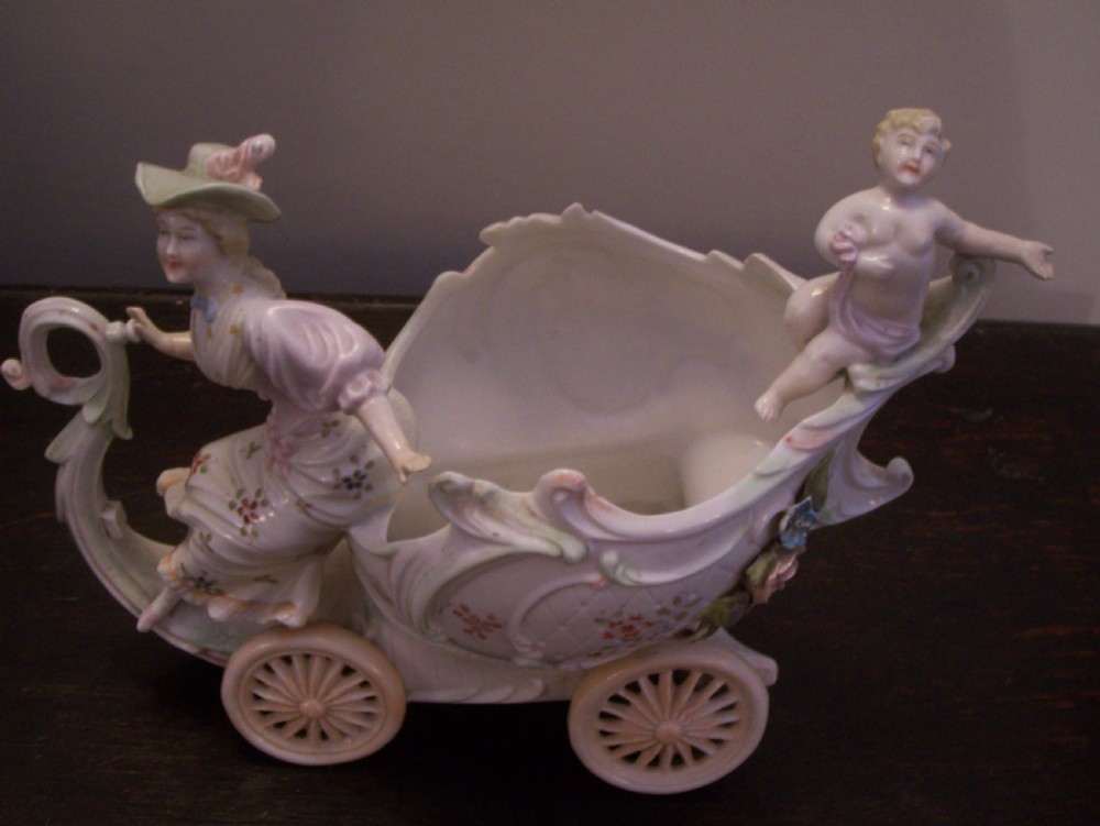 A pair of 19th-century pastel porcelain chariot vases featuring sculpted male and female figures with cherubs and scroll details. View V