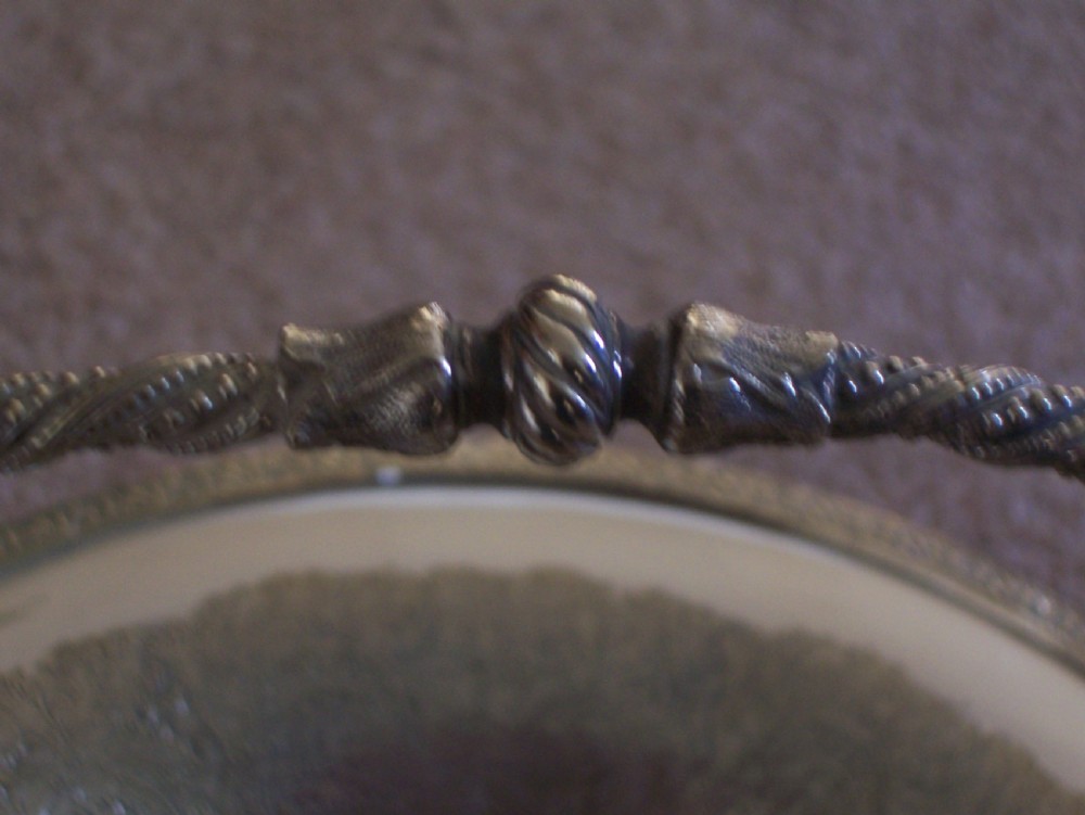 A Victorian silver-plated oval cake basket featuring a twisted overhead swing handle and a raised pedestal base. View V