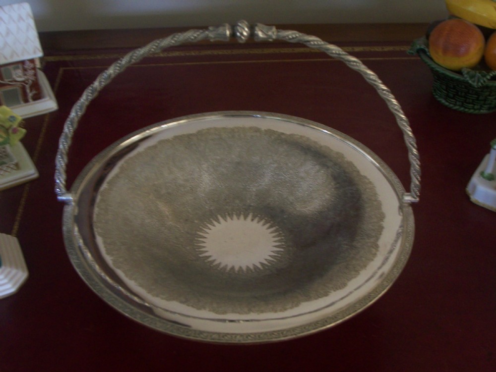 A Victorian silver-plated oval cake basket featuring a twisted overhead swing handle and a raised pedestal base. View VIII
