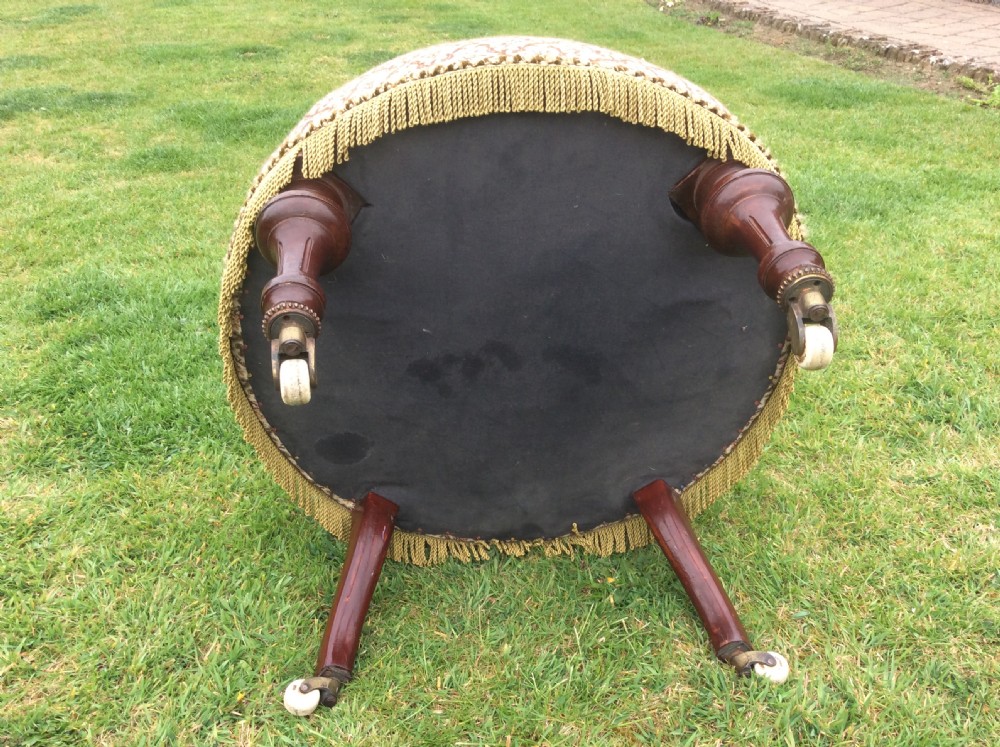 A Victorian low-seated nursing chair featuring a dark mahogany spindle back, padded top rail, pattern-upholstered seat with fringe trim, and turned front legs with castors. View IV