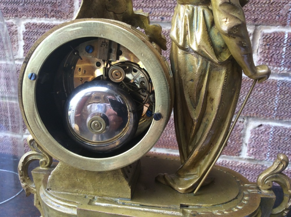 A mid nineteenth-century French gilt ormolu mantel clock featuring a classical figure, blue Sevres-style porcelain dial, and panels, set under a clear glass dome on a wooden base. View VI