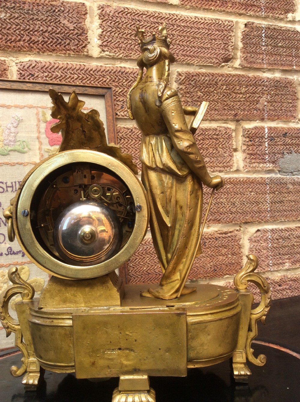 A mid nineteenth-century French gilt ormolu mantel clock featuring a classical figure, blue Sevres-style porcelain dial, and panels, set under a clear glass dome on a wooden base. View XI