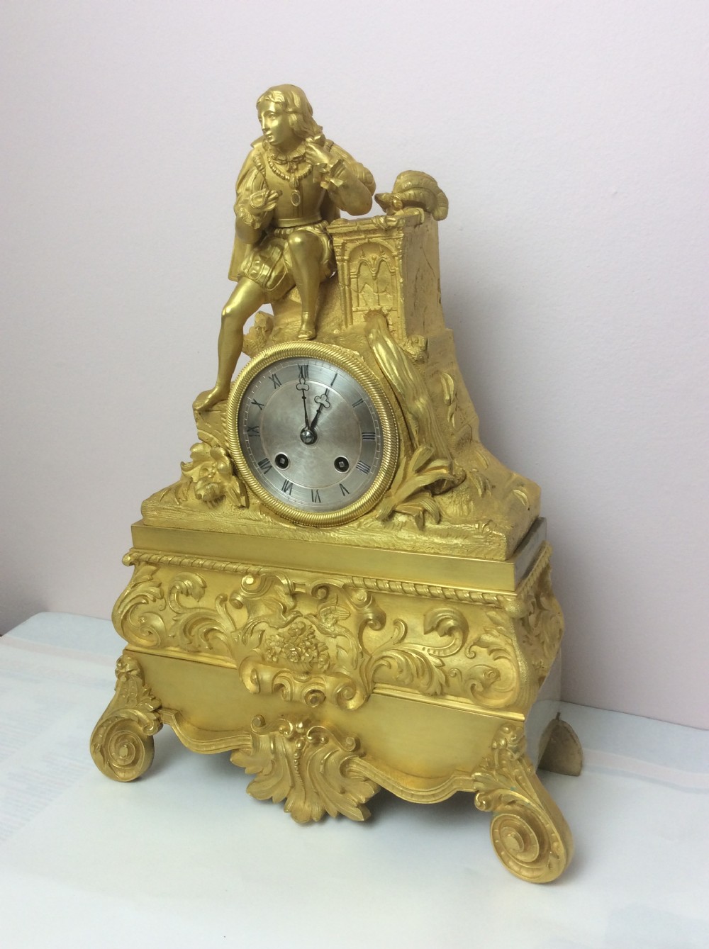 A gilt bronze French Empire mantel clock featuring a sculpted explorer figure sitting above a silvered dial on an ornate scrollwork base. View II