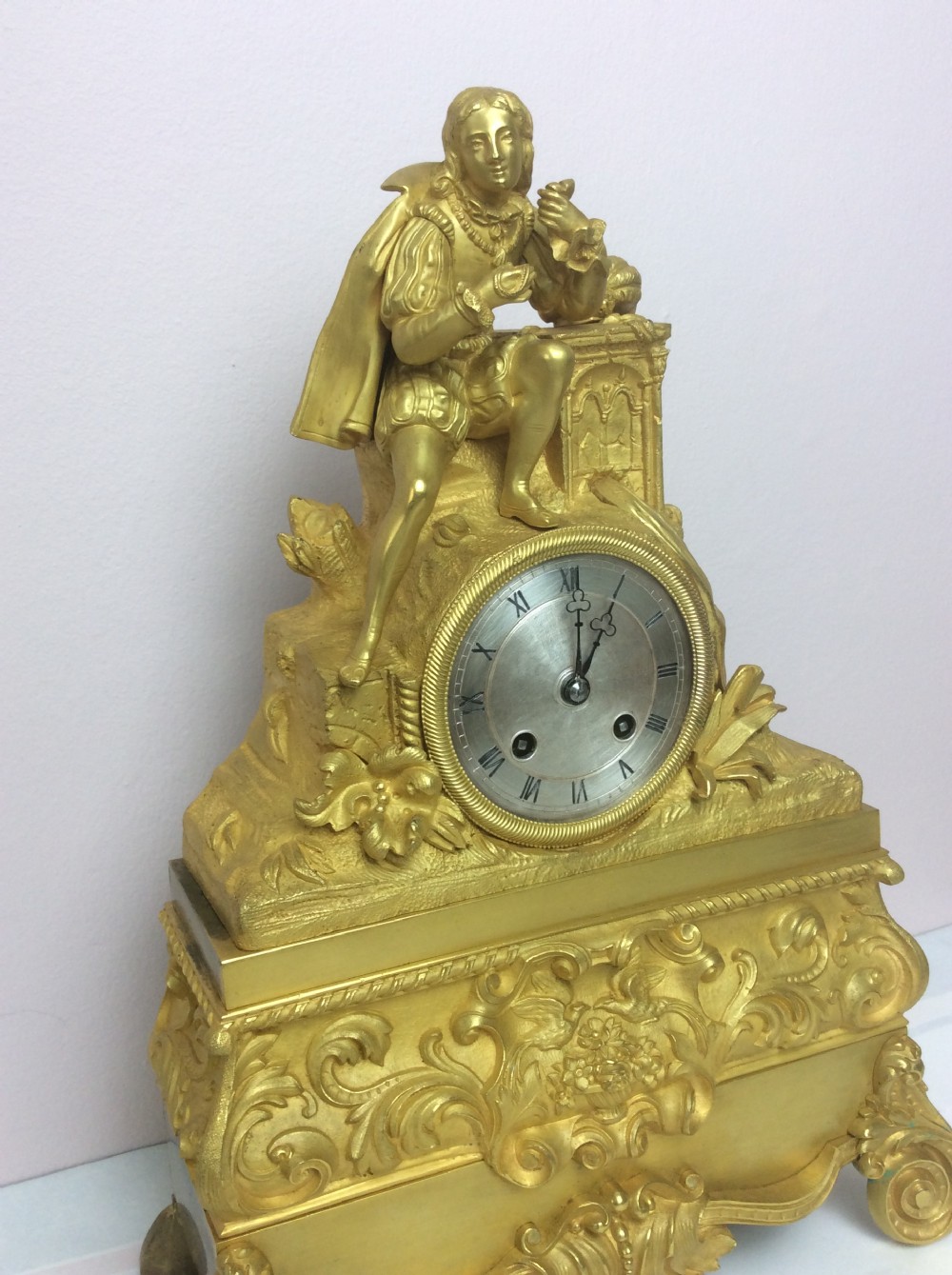 A gilt bronze French Empire mantel clock featuring a sculpted explorer figure sitting above a silvered dial on an ornate scrollwork base. View III