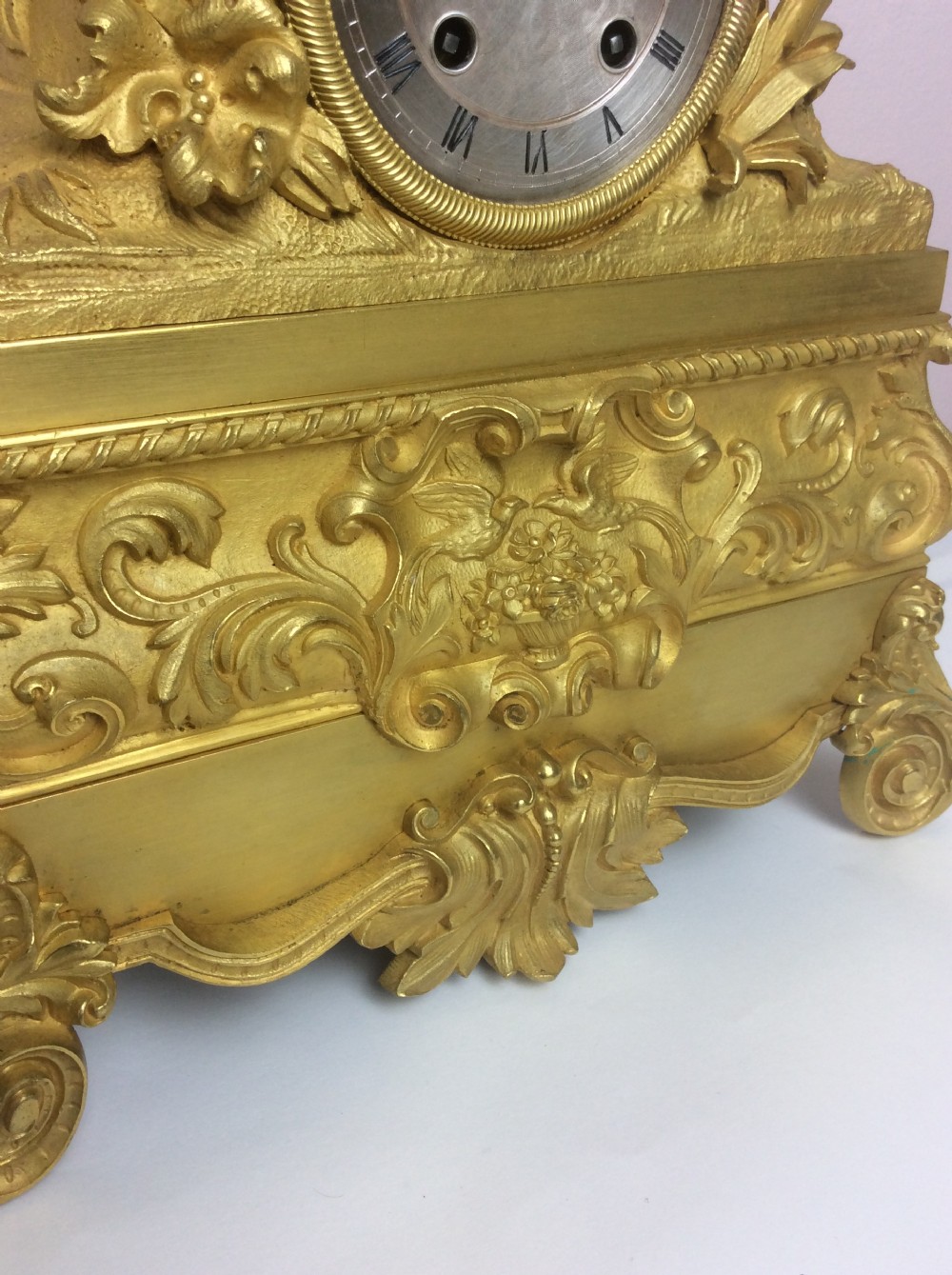 A gilt bronze French Empire mantel clock featuring a sculpted explorer figure sitting above a silvered dial on an ornate scrollwork base. View IV